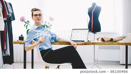 Happy dressmaker with laptop in studio 86180466