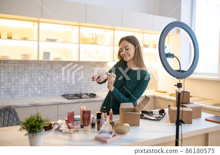 Pretty woman demonstrating new cosmetics and looking involved Pretty woman demonstrating new cosmetics and looking involved 86180575