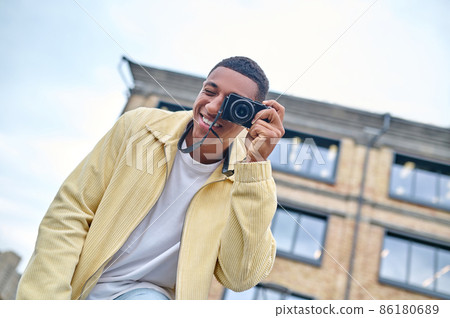 Man looking through camera lens outdoors 86180689