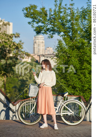 A young girl standing near the bike in the street A young girl standing near the bike in the street 86180721