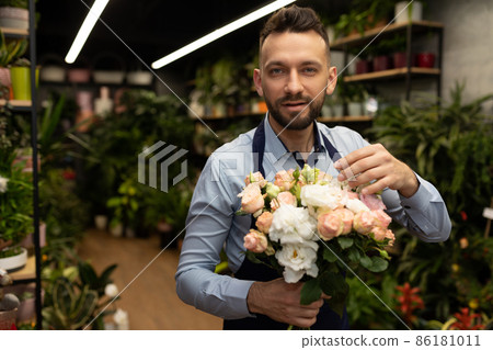 a man in an apron with a bouquet of flowers in front of a garden shop a man in an apron with a bouquet of flowers in front of a garden shop 86181011