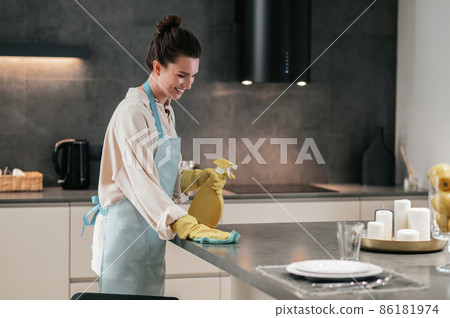 Young dark-haired woman disinfecting the surfaces in the kitchen 86181974