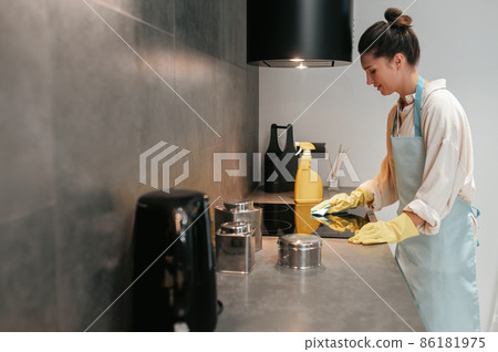 Young dark-haired woman disinfecting the surfaces in the kitchen 86181975