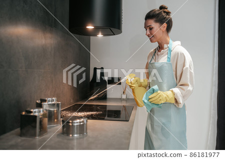 Young dark-haired woman disinfecting the surfaces in the kitchen 86181977