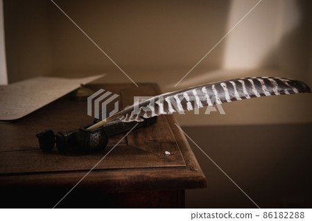 Quill pen in ink bottle on the table, close-up. 86182288