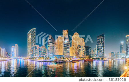 Beautiful Night view of high-rise buildings of residential district in Dubai Marina And Tourist Boat, Sightseeing Boat Sailing On Dubai Marina. Panorama, Panoramic View 86183026