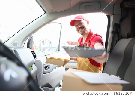 Male courier in uniform picking up documents from car Male courier in uniform picking up documents from car 86183107
