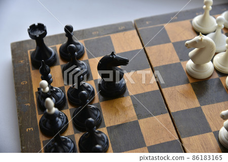 An old chessboard with white and black pieces 86183165