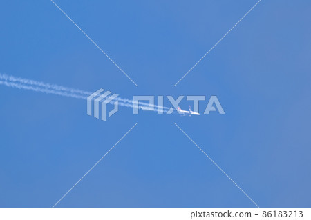 Distant passenger jet plane flying on high altitude on clear blue sky leaving white smoke trace of contrail behind. Air transportation concept Distant passenger jet plane flying on high altitude on clear blue sky leaving white smoke trace of contrail behind. Air transportation concept 86183213