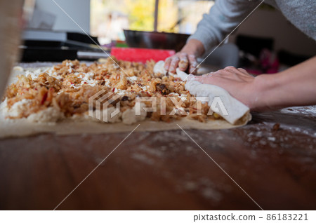 Rolling apple filled pastry dough into a strudel 86183221