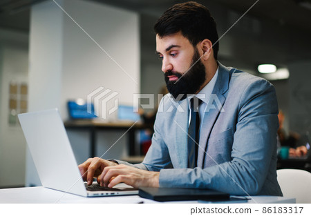 Focused businessman using laptop for work 86183317
