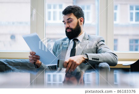 Serious entrepreneur reading document in office Serious entrepreneur reading document in office 86183376
