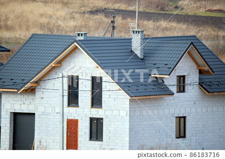 Aerial view of house roof top covered with ceramic shingles. Tiled covering of building under construction Aerial view of house roof top covered with ceramic shingles. Tiled covering of building under construction 86183716