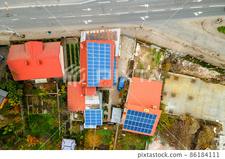 Aerial view of residential houses with rooftops covered with solar photovoltaic panels in suburban rural area 86184111