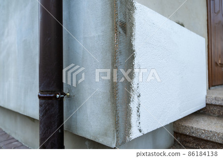 Installation of styrofoam insulation sheets on house facade wall for thermal protection. Installation of styrofoam insulation sheets on house facade wall for thermal protection. 86184138