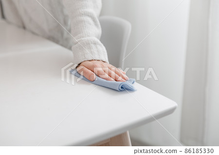 Cleaning the table with a blue microfiber cloth. Sanitize surfaces prevention in hospital and public spaces against coronavirus. Woman hand using wet wipe at home. Cleaning the room. 86185330