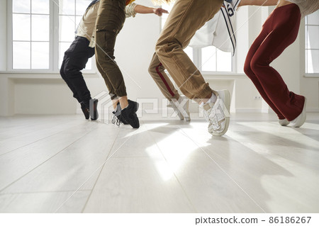 Youth dances. Group of hip hop dancers who together perform stand on toes during rehearsal in dance studio. Low section of legs of young people in casual clothes who simultaneously stand on their toes Youth dances. Group of hip hop dancers who together perform stand on toes during rehearsal in dance studio. Low section of legs of young people in casual clothes who simultaneously stand on their toes 86186267