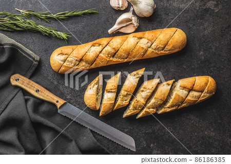 Roasted baguette with garlic butter. Crunchy sliced garlic bread on black table. 86186385