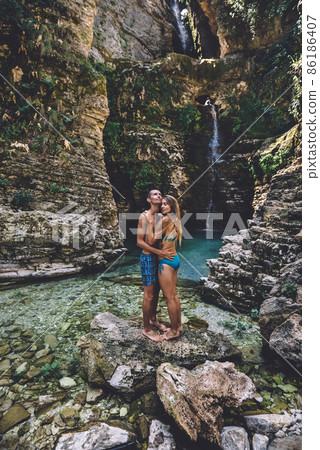 Young Couple in Hugging at Wild Waterfall Young Couple in Hugging at Wild Waterfall 86186407