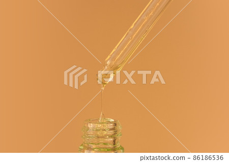 Pipette with transparent fluid hyaluronic acid or serum. Cosmetics, science and healthcare concept closeup. Dose of green serum or retinol falls in bottle. Front view. Beauty product presentation Pipette with transparent fluid hyaluronic acid or serum. Cosmetics, science and healthcare concept closeup. Dose of green serum or retinol falls in bottle. Front view. Beauty product presentation 86186536