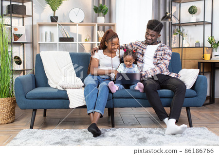 Happy african american family using laptop on couch Happy african american family using laptop on couch 86186766