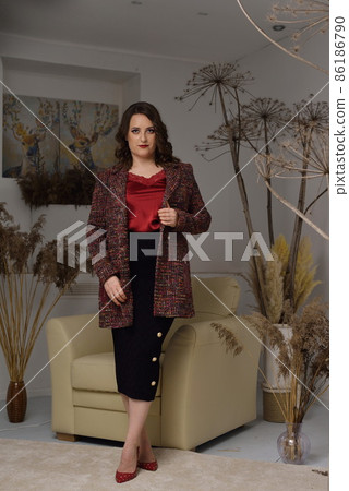 A beautiful young girl posing in a light armchair. 86186790