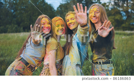 Cheerful girls posing smeared in multi-colored powder. 86186863