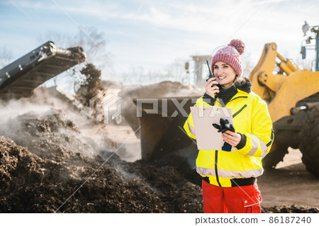 Manager in biomass and landfill operation using her radio in front of machines Manager in biomass and landfill operation using her radio in front of machines 86187240