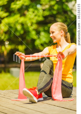 Girl doing exercise outdoor, using resistance fit band. 86188335