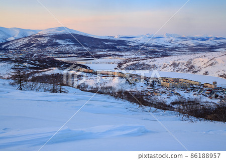 Evening landscape with a town in the valley among the mountains. Magadan, Far East of Russia. 86188957