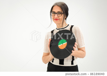 Studio photo of middle aged woman starting getting grey-haired wearing black and white clothes with vinyl record in hands on white background, middle age sexy lady, happy life concept Studio photo of middle aged woman starting getting grey-haired wearing black and white clothes with vinyl record in hands on white background, middle age sexy lady, happy life concept 86189040