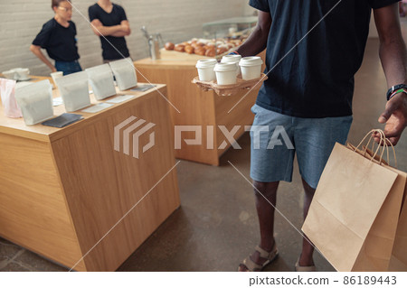 Negro courier holding grocery bags and cups of tea 86189443