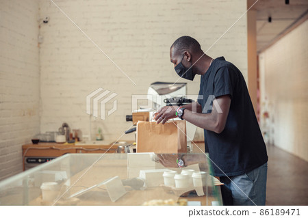 Black man cheking boxes of customers in pandemic 86189471