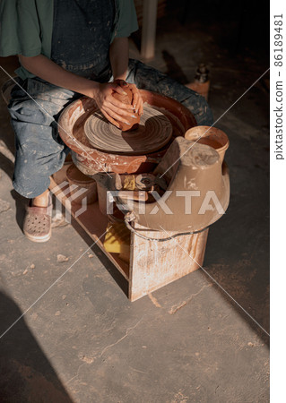 Woman potter shaping clay on pottery wheel in atelier Woman potter shaping clay on pottery wheel in atelier 86189481