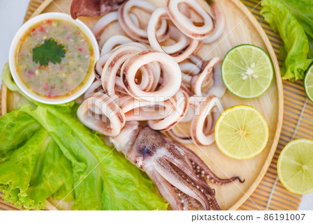 squid rings on wooden plate, Fresh squid cooked boiled with lettuce vegetable salad lemon and seafood sauce on table background squid rings on wooden plate, Fresh squid cooked boiled with lettuce vegetable salad lemon and seafood sauce on table background 86191007