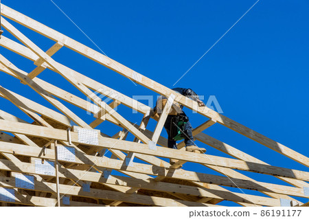 Roofer working with framing installing the roof truss system 86191177