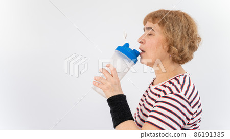 Elderly woman drinks water while exercising on white background. 86191385