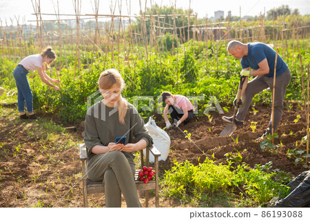 Young woman resting in garden using smartphone 86193088