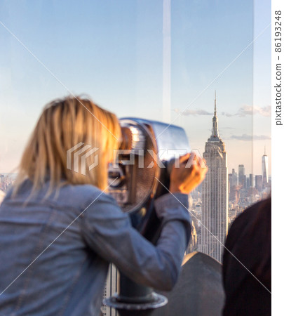 New york, USA - May 17, 2019: New york, USA - May 17, 2019: Rear View of Woman looking Through Binocular View Finder at New York City Skyline New york, USA - May 17, 2019: New york, USA - May 17, 2019: Rear View of Woman looking Through Binocular View Finder at New York City Skyline 86193248