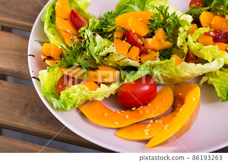 Salad of baked pumpkin, cherry tomatoes, sesame, sauce and greens Salad of baked pumpkin, cherry tomatoes, sesame, sauce and greens 86193263