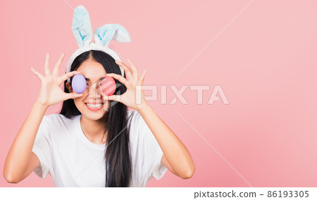 woman smiling wearing rabbit ears holding colorful Easter eggs front eyes woman smiling wearing rabbit ears holding colorful Easter eggs front eyes 86193305