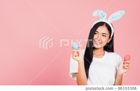 woman smiling wearing rabbit ears holding colorful Easter eggs gift on hands 86193306