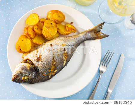 Baked fish called Dorada with toasted potatoes 86193540