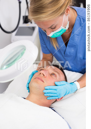 Woman doctor is massaging face of patient after the procedure Woman doctor is massaging face of patient after the procedure 86193906