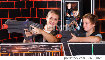 positive teen boy having fun on laser tag arena with his older sister positive teen boy having fun on laser tag arena with his older sister 86194025