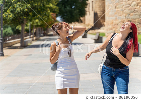 Cheerful women walking along street in city Cheerful women walking along street in city 86196056