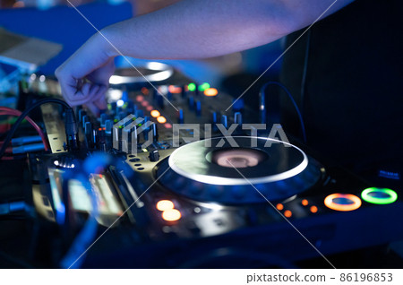 Dj mixing at party festival with light and smoke in background - Summer nightlife view of disco club Dj mixing at party festival with light and smoke in background - Summer nightlife view of disco club 86196853