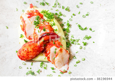 Chunks of cooked cut lobster meat served on a plate. 86196944