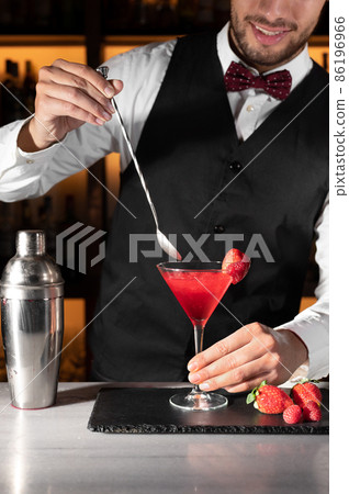Young barman serving a cocktail at night club. 86196966
