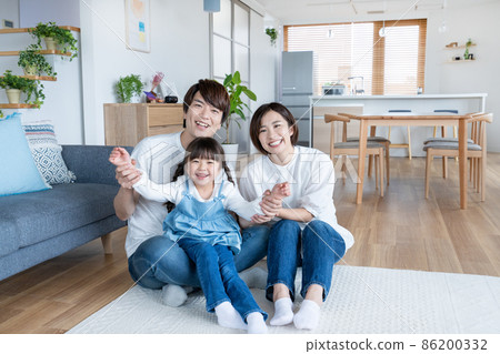 Portrait of elementary school girl, dad and mom sitting and playing in the living room at home 86200332